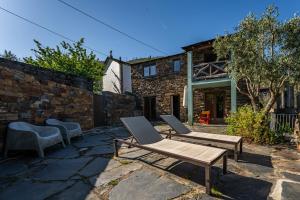 a patio with two chairs and a bench and a building at Casa da Figueira - Rio Paiva in Arouca