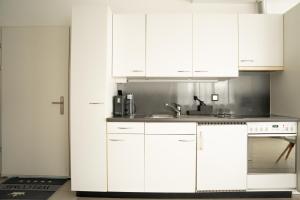 a white kitchen with white cabinets and a sink at Ufer Nest in Buochs in Buochs +4 photos