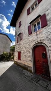 a brick building with a red door and windows at Casa Stella in Venzone