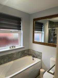 a bathroom with a bath tub and a mirror at Old Schoolhouse Coleraine in Coleraine +17 photos