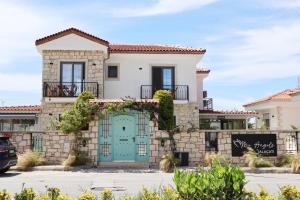 a house with a green door and a stone wall at My Angels Alaçatı in Alaçatı
