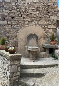 a stone wall with a bench and a stone fireplace at CAN PINÓS de GUIMERÀ in Guimerá