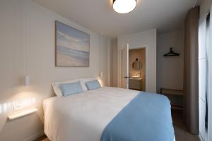 a bedroom with a white bed with a blue blanket at Maison Dieu in Hasselt
