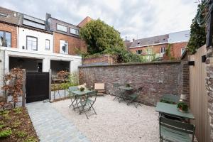 a courtyard with a brick wall and tables and chairs at Maison Dieu in Hasselt