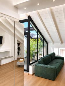 ein Wohnzimmer mit einem grünen Sofa und großen Fenstern in der Unterkunft Sebì Suite in Iseo