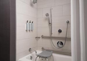 a bathroom with a shower with a stool in it at Courtyard by Marriott Boston Brookline in Brookline