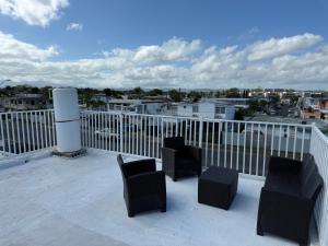 a balcony with chairs and tables on a roof at Shalex House 2 in Carolina