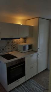 a kitchen with white cabinets and a microwave at Le Mura Holiday Home in Marina di Pietrasanta