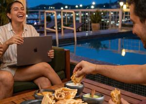 a man and a woman sitting at a table with a laptop at MuchoSur Santa Marta in Santa Marta