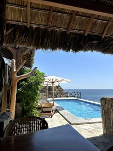 a swimming pool with a table and chairs and the ocean at Casa Mario Alberto - Oceanfront Bungalows in Puerto Ángel