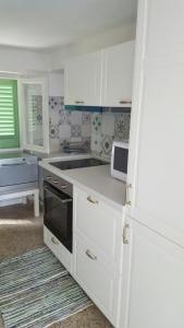 a kitchen with white cabinets and a white microwave at Le Mura Holiday Home in Marina di Pietrasanta