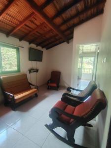 a living room with chairs and a couch and a television at Hostal El Renacer in Pinchote