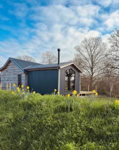 a house with a bench in a field with flowers at Clover in Wrenbury