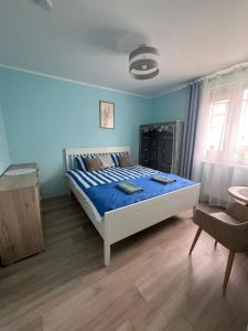 a blue bedroom with a bed and a chair at Przystanek Hel in Hel