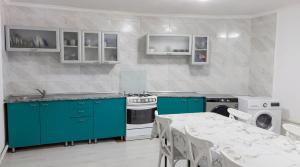 a kitchen with green cabinets and a table and a stove at Almaty Backpackers in Almaty