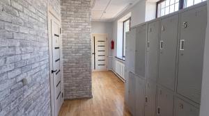 a hallway with gray lockers and a brick wall at Almaty Backpackers in Almaty