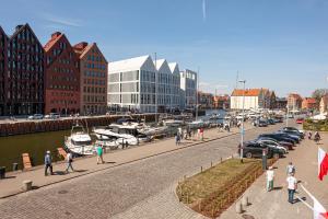 a group of people walking on a sidewalk next to a marina at House of Zen - Apartament z widokiem na Motławę i Stare Miasto in Gdańsk