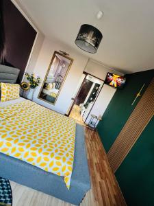 a small room with a bed with a yellow and white pattern at Apartament Gossip XOXO in Galaţi