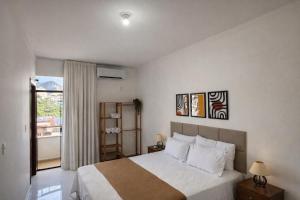 a bedroom with a large white bed and a window at Super Apt morada do Vale in Governador Valadares