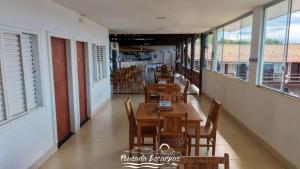 a restaurant with wooden tables and chairs and windows at Suíte com Jacuzzi Vista de Escarpas 3 in Capitólio