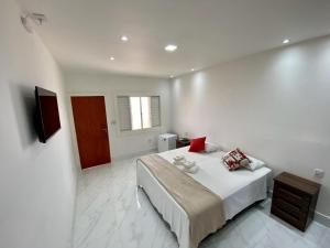 a white bedroom with a bed and a television at Suíte com Jacuzzi Vista de Escarpas 3 in Capitólio