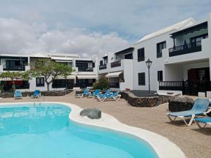 ein Schwimmbad mit Stühlen und ein Gebäude in der Unterkunft Casa jablillo in Costa Teguise