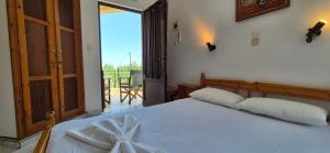 a bedroom with a white bed and a balcony at Mary's House in Vourliótai