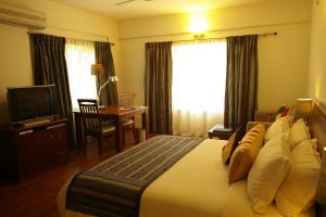 a bedroom with a bed and a desk and a television at juSTa Off MG Road in Bangalore