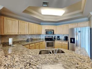 a kitchen with wooden cabinets and a granite counter top at The Oasis Orange Beach 2110 in Orange Beach +41 photos
