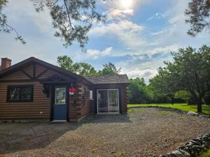 a log cabin with a blue door on a gravel driveway at For-Rest Inn and Spa in Bathurst