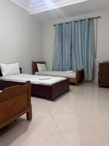 two beds in a room with blue curtains at Rmilate Coast Apartment in Asilah