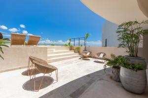 a patio with chairs and potted plants on a building at Oniric Condo Tulum in Tulum