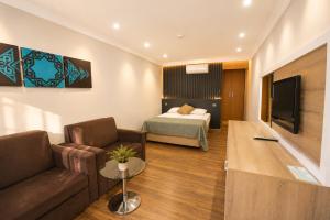 a hotel room with a bed and a couch and a tv at Fii Suites in Kumluca