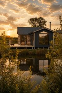 a log cabin with a pond in front of it at Iris - The Nook Lodges in Nantwich
