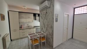 a kitchen with white cabinets and a table in it at Ladispoli Apartment in Ladispoli