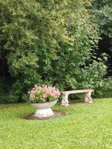 a stone bench sitting in the grass with pink flowers at Sérénité in Corquilleroy +6 photos