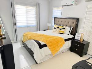 a bedroom with a large bed with yellow blankets and pillows at The Perrys Chateau in Old Harbour