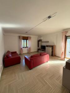 a living room with two red couches and a kitchen at Home Marí in Sessa Aurunca
