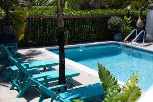 a swimming pool with chairs and a palm tree in it at Palm Breeze Hotel in Lake Worth
