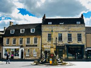 an old building with a fountain in the middle of a street at NEW Stylish Cosy Dog Friendly Cottage Parking Central in Oundle +28 photos