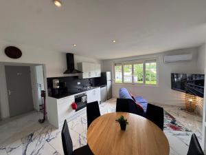 a living room with a wooden table and a kitchen at T3 moderne - Clim - Parking privé 4 couchages in Decazeville
