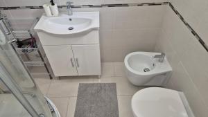 a white bathroom with a toilet and a sink at Ladispoli Apartment in Ladispoli