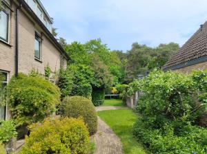 a garden with bushes and trees next to a house at VolopVeluwe in Ermelo