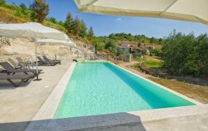 a swimming pool with an umbrella and a house at Riverside Lodges - Serra da Estrela - Chão da Ribeira in Gouveia