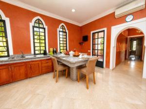 a large kitchen with a table and chairs and orange walls at Mila Dyafa in Oulad Akkou