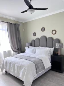 a bedroom with a large bed with a ceiling fan at Heaven on Windermere in Durban +10 photos