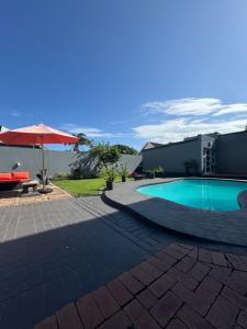 a swimming pool with a table and an umbrella at Heaven on Windermere in Durban