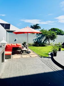 a patio with a red couch and an umbrella at Heaven on Windermere in Durban