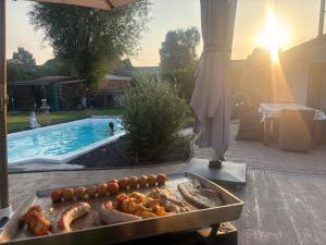 ein Grill mit Essen darauf neben einem Schwimmbecken in der Unterkunft Ostivigne in Ath