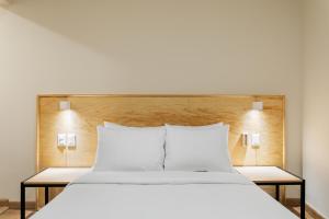 a large bed with white pillows and two tables at Madero By Homirent in Querétaro